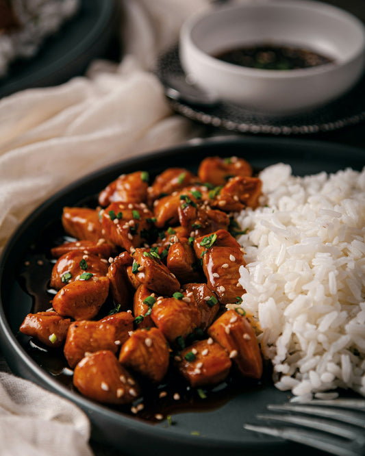 Hawaiian shoyu chicken glazed in salty-sweet soy sauce, served over white rice with green onions and sesame seeds