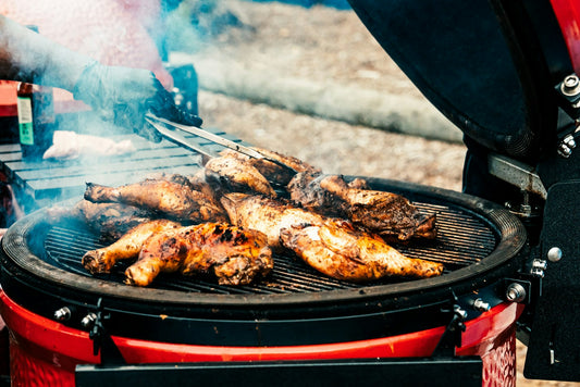 Jamaican jerk chicken drumsticks grilling over charcoal with smoke